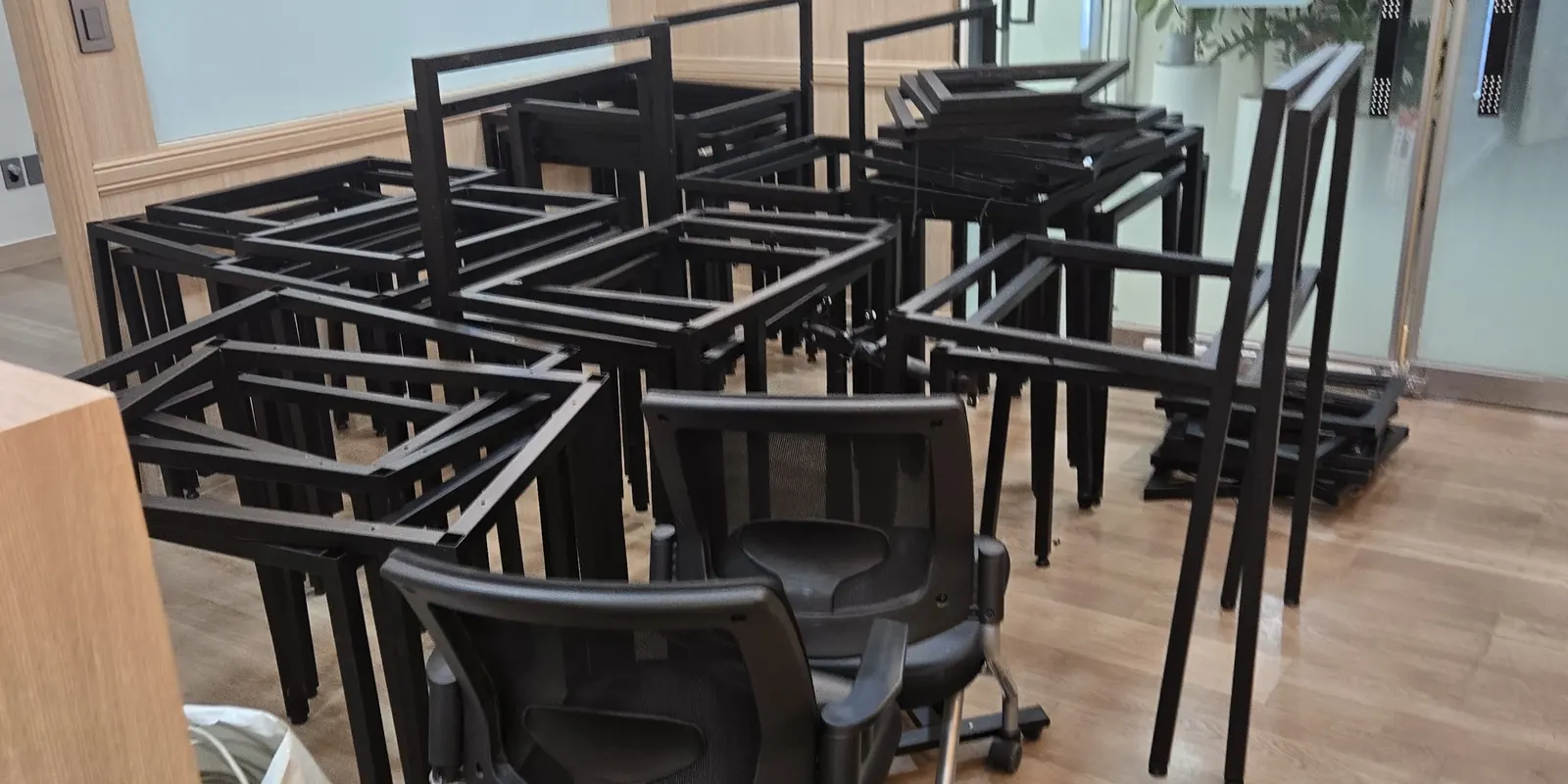 학원에서 분리해 모아 둔 검정 철제 프레임과 사무용 의자가 우드 톤 실내에 놓인 현장 사진