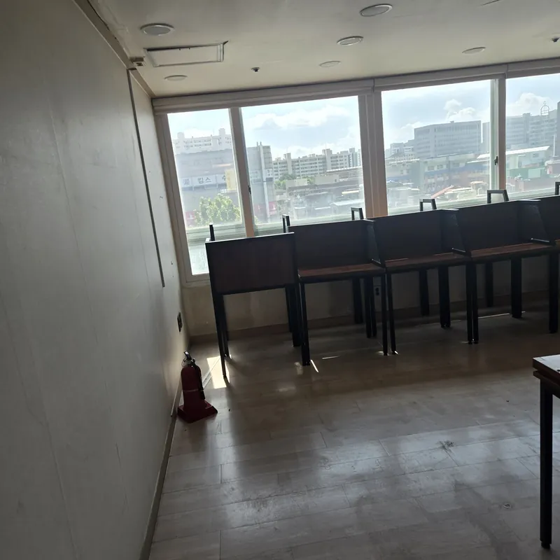 학원폐업철거 현장 · 창가에 책상과 의자가 놓인 실내와 벽면의 소화기