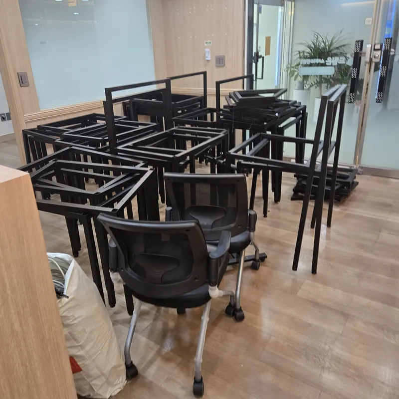 학원집기철거 · 우드 톤 실내 바닥에 쌓여 있는 검정 철제 프레임과 사무용 의자